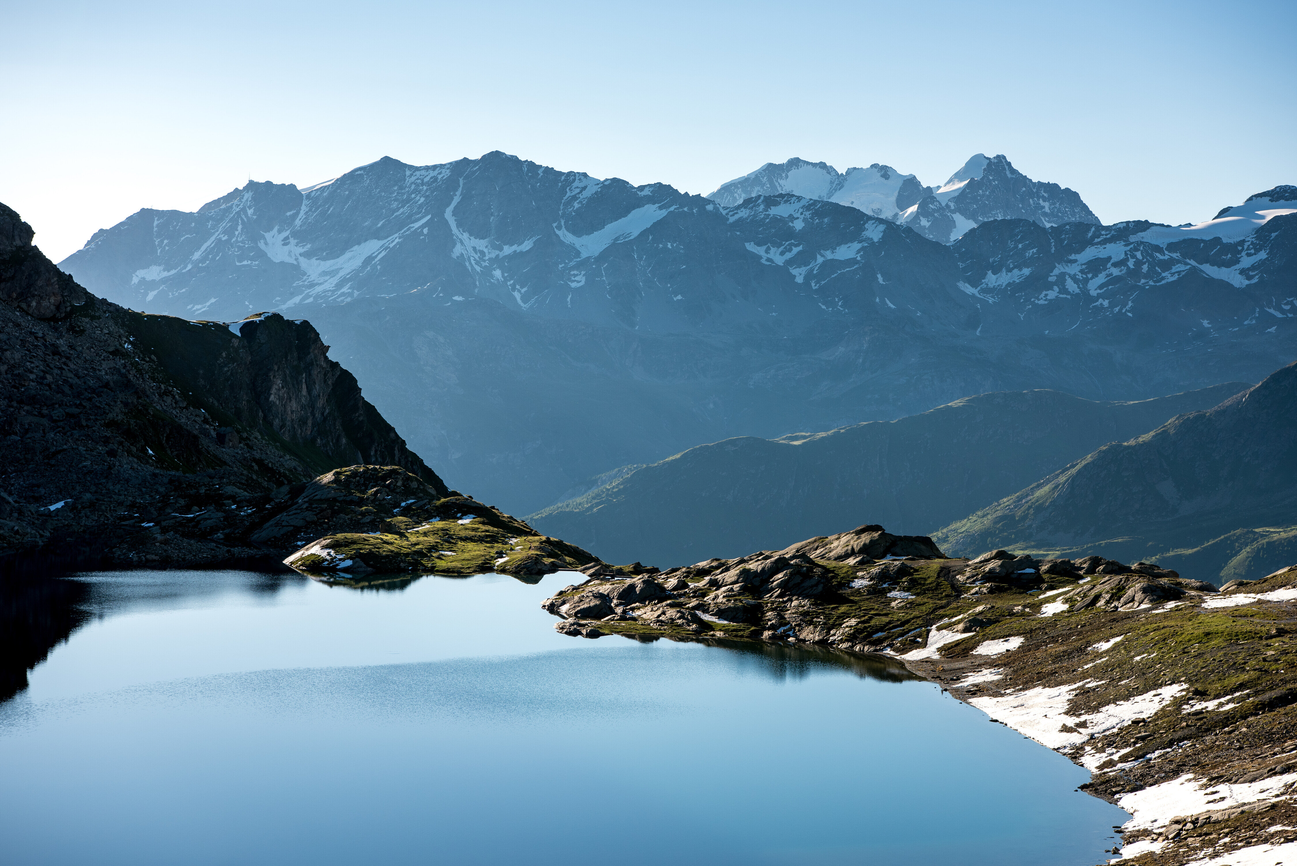 Stiller Bergsee vor schneebedeckten Gipfeln