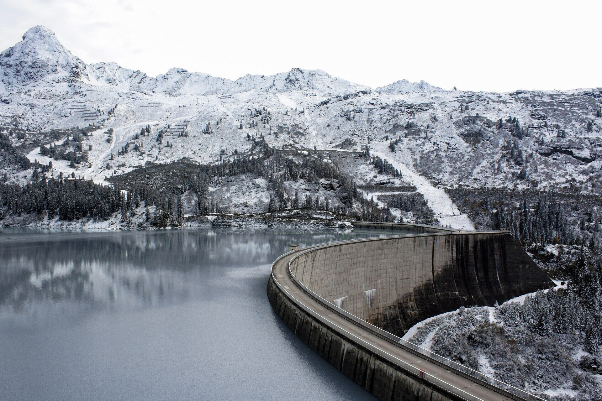 Staumauer und Stausee in winterlicher Berglandschaft